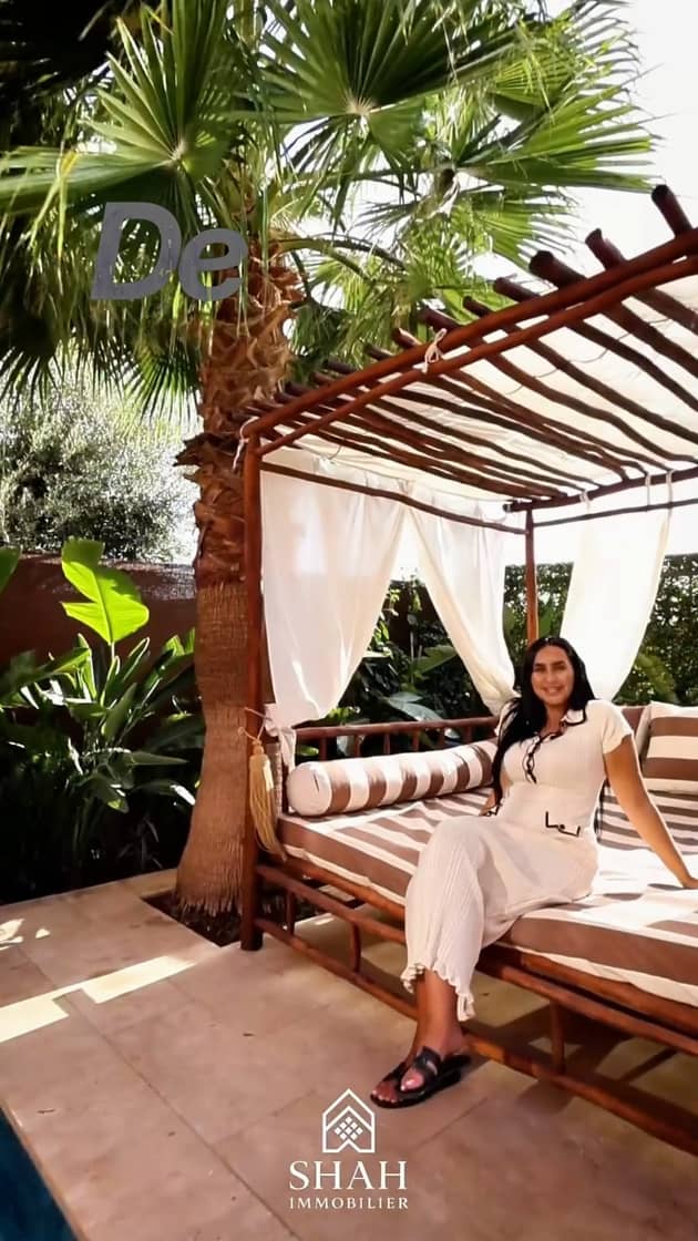 Piscine privée avec lit de jour sous pergola en bois et palmier